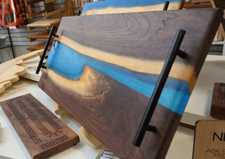 Wooden cribbage board with blue stripe and black rails on a table.