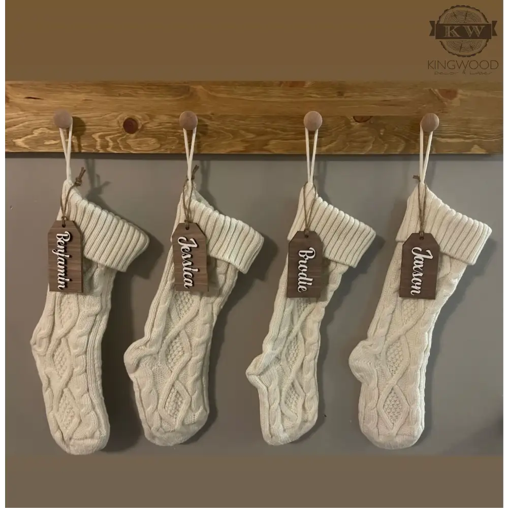 Four white knit Christmas stockings with a laser cut custom wooden Christmas stocking tag