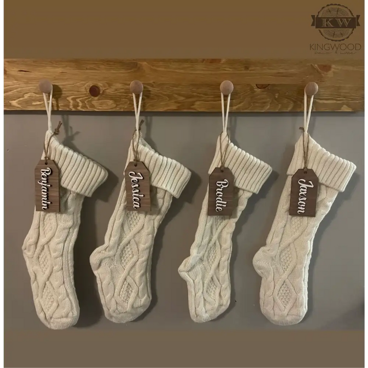 Four white knit Christmas stockings with a laser cut custom wooden Christmas stocking tag
